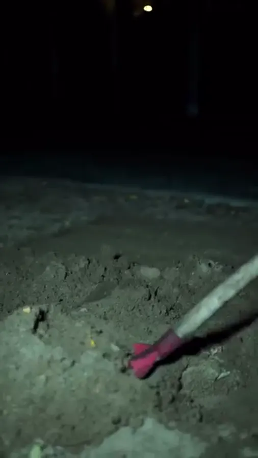Tournage de nuit : une silhouette en manteau translucide qui creuse à la pelle